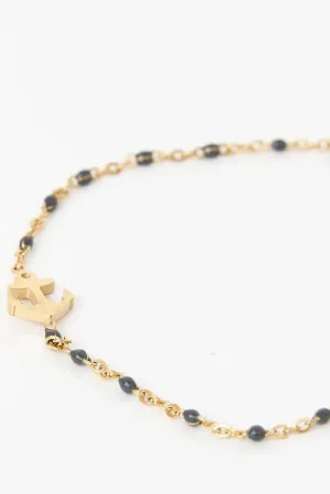 Pulsera o brazalete color dorado con ancla, piedra azul.
